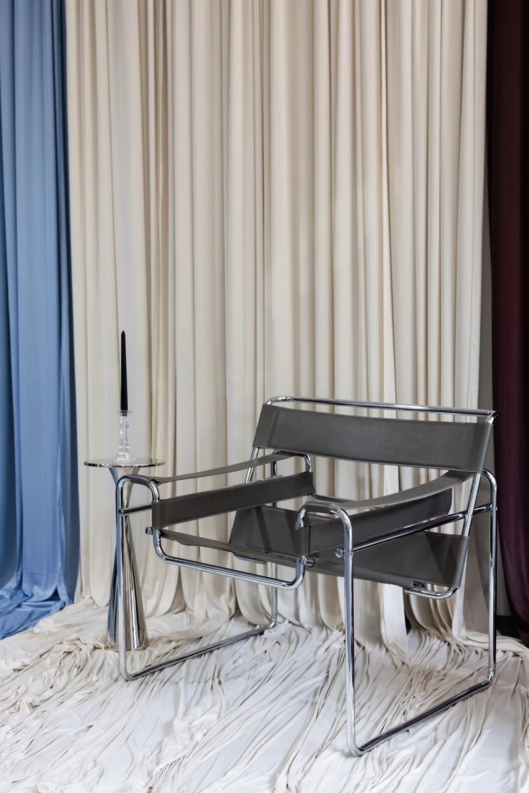 Photo set with cream curtains, a draped floor and a leather sling chair