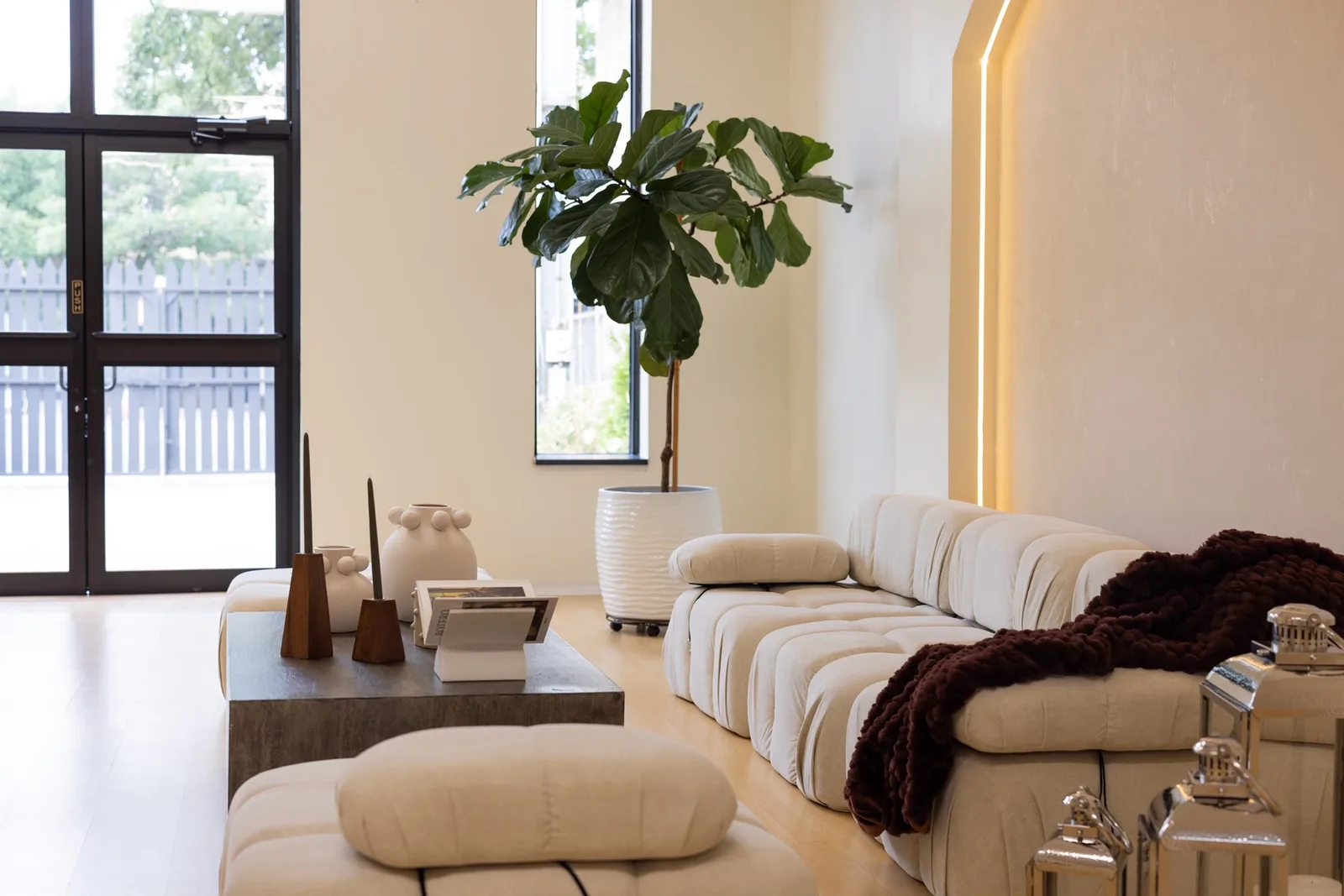 Living room with a cream modular sofa, a fiddle-leaf fig and a low wooden table